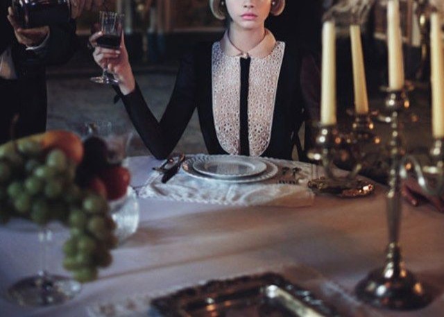 cropped W Mag cover of woman being poured a glass of wine at a formal dining table in a dark room