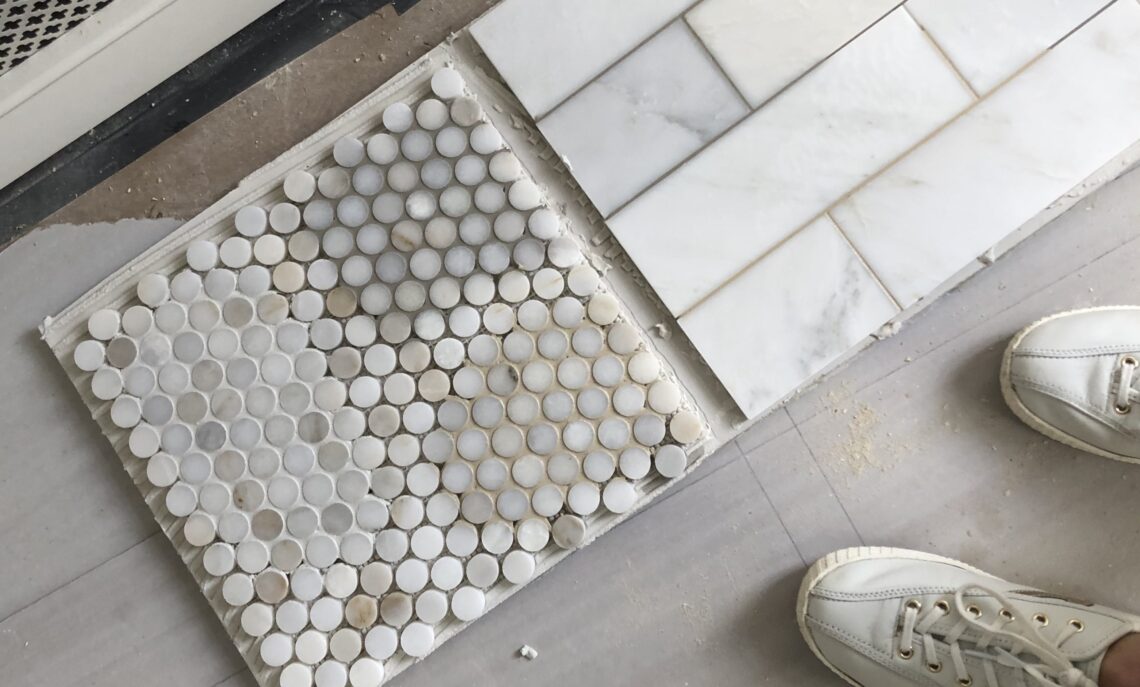 penny and subway marble tiles on floor with varying grout colors applied as samples