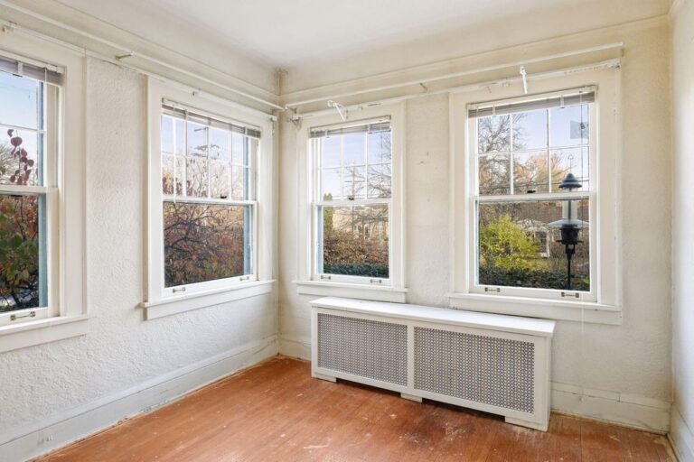 small den surrounded by windows with wood floors and radiator